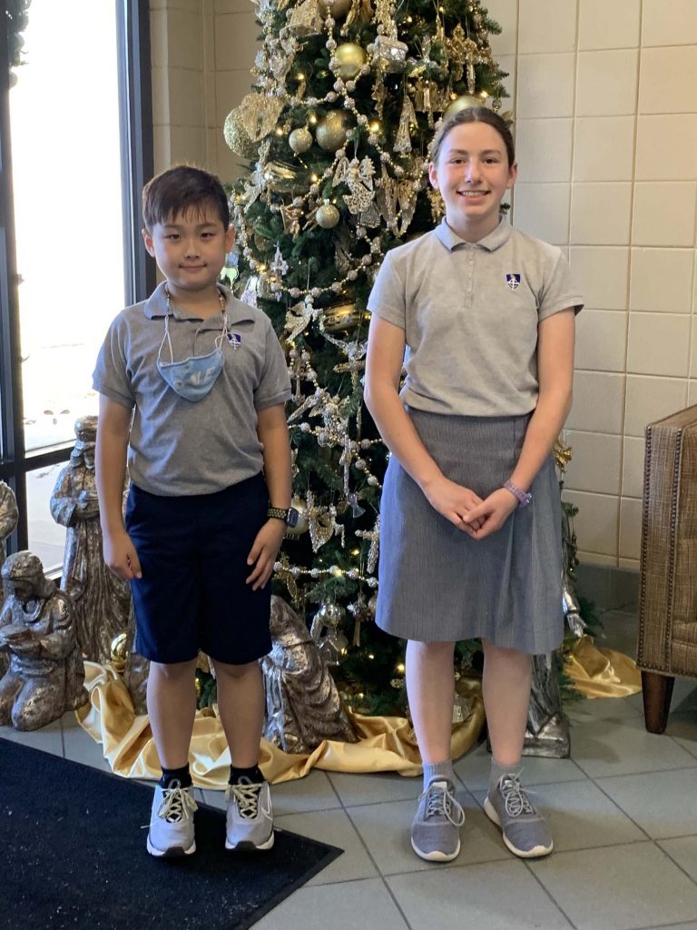 two children standing in front of a christmas tree